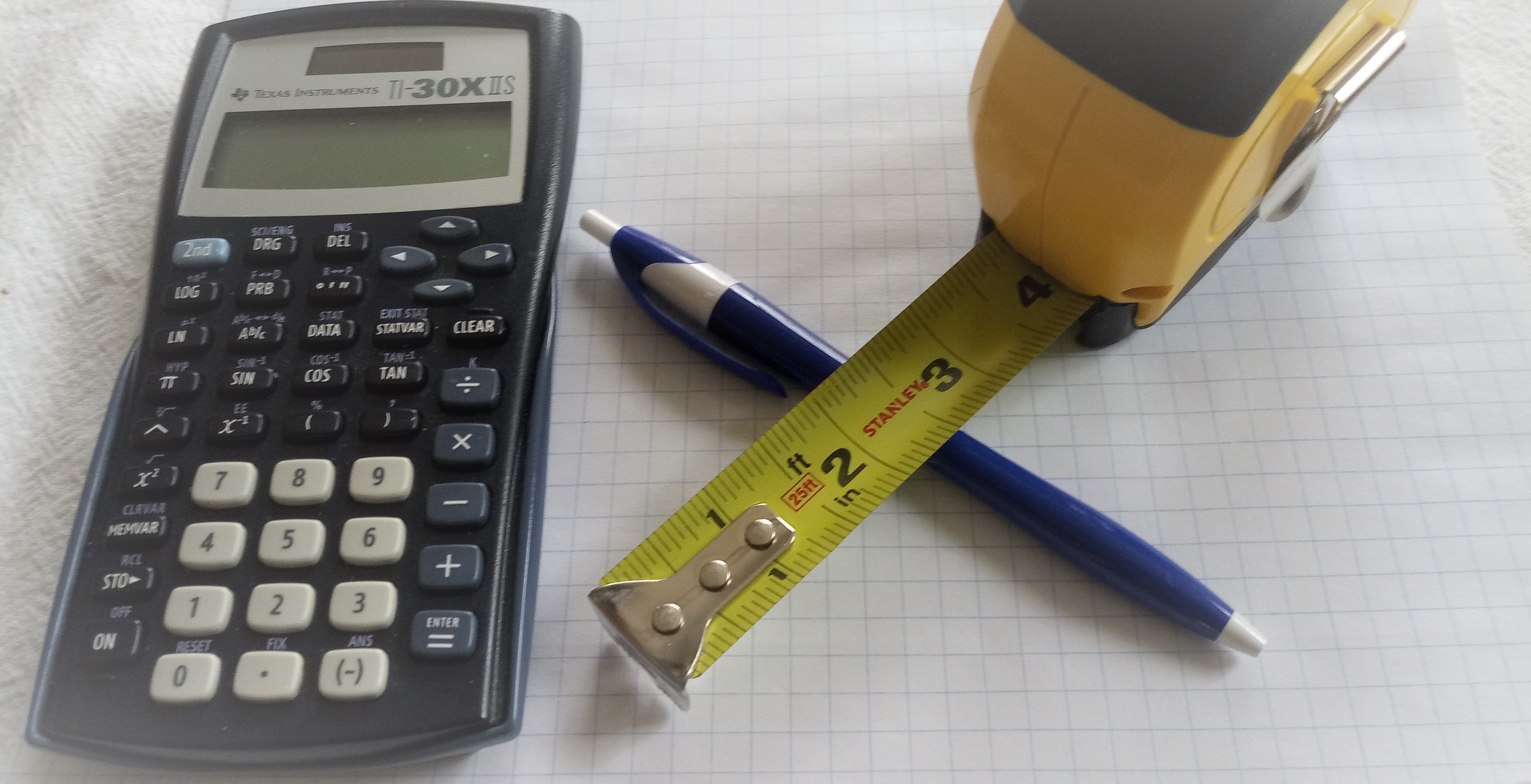 Calculator, pen, and measuring tape on graph paper